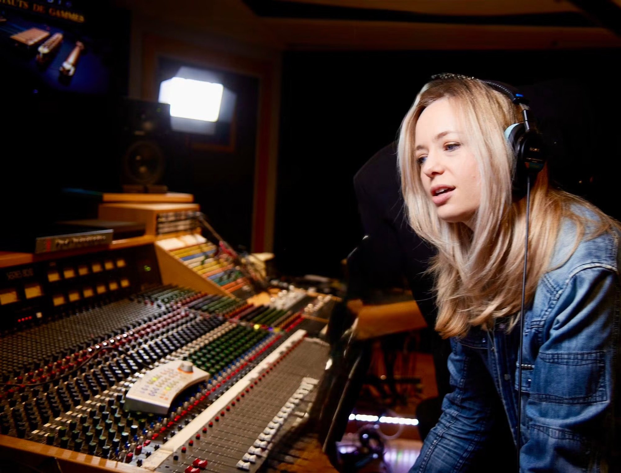 Céline Magnano en studio, casque sur les oreilles, devant une console de mixage